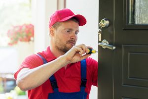 locksmith in red uniform installing new house door lock