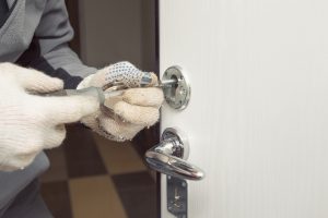 Locksmith in rag gloves changes the door locks.